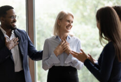Middle aged businesswoman get congrats and compliments from multiethnic colleagues